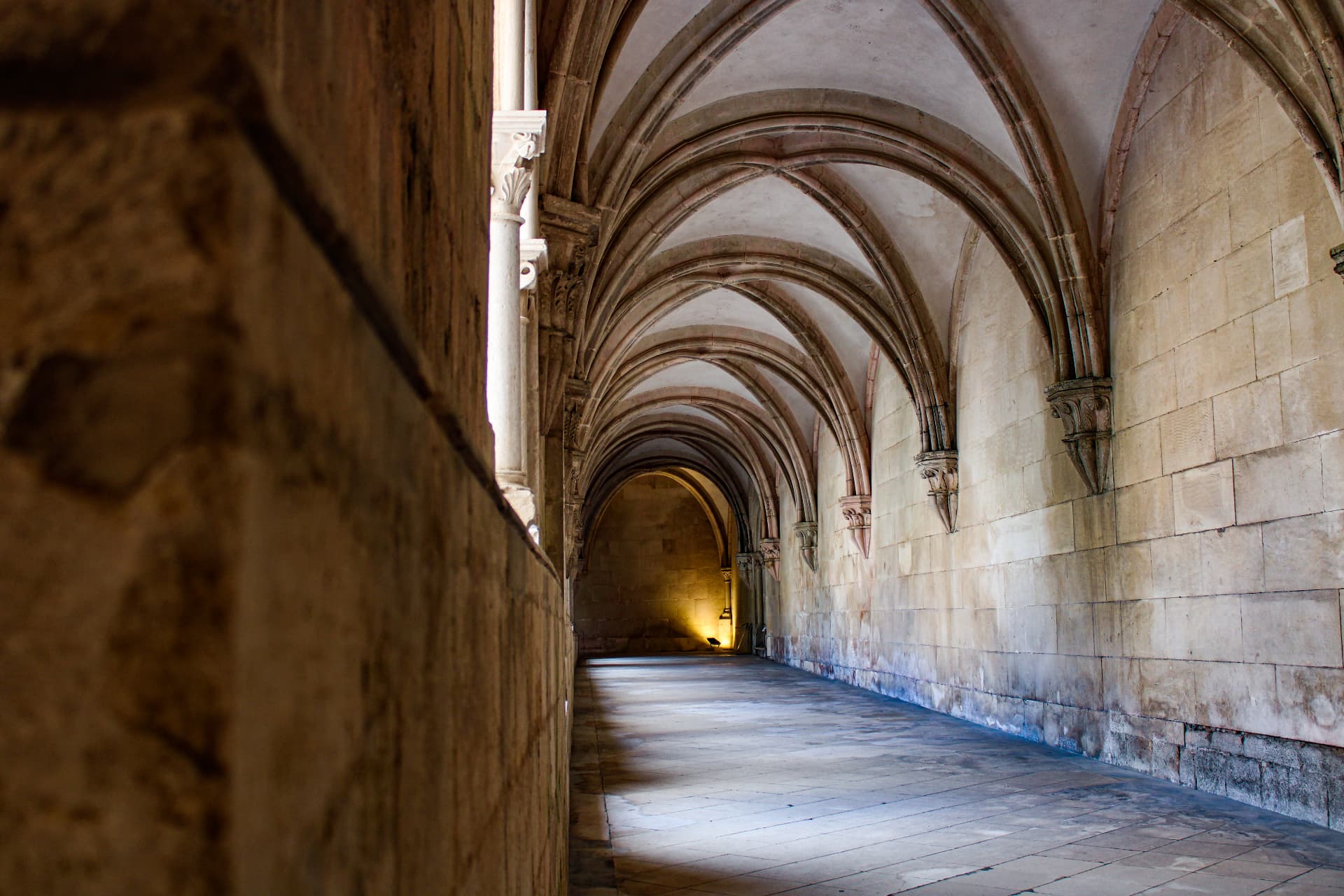 Ribbed stone vaults along a monastery cloister corridor in Portugal
